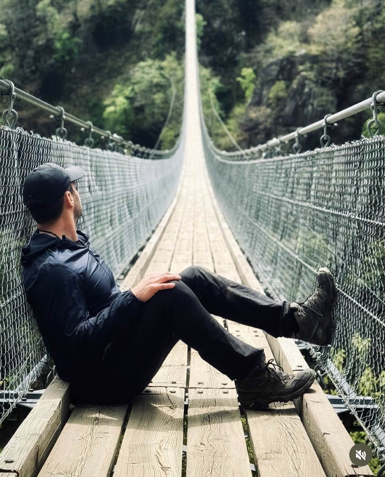 Person sitzt auf einer Hängebrücke