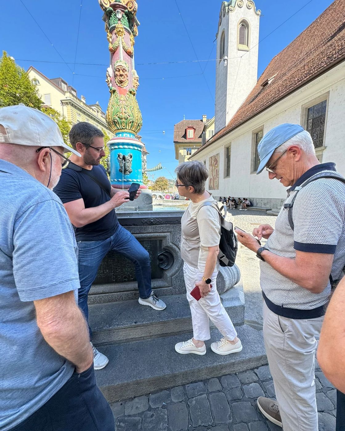 Roman Beer zeigt einer Kursgruppe am Fritschibrunnen in der Luzerner Altstadt eine Einstellung am Smartphone