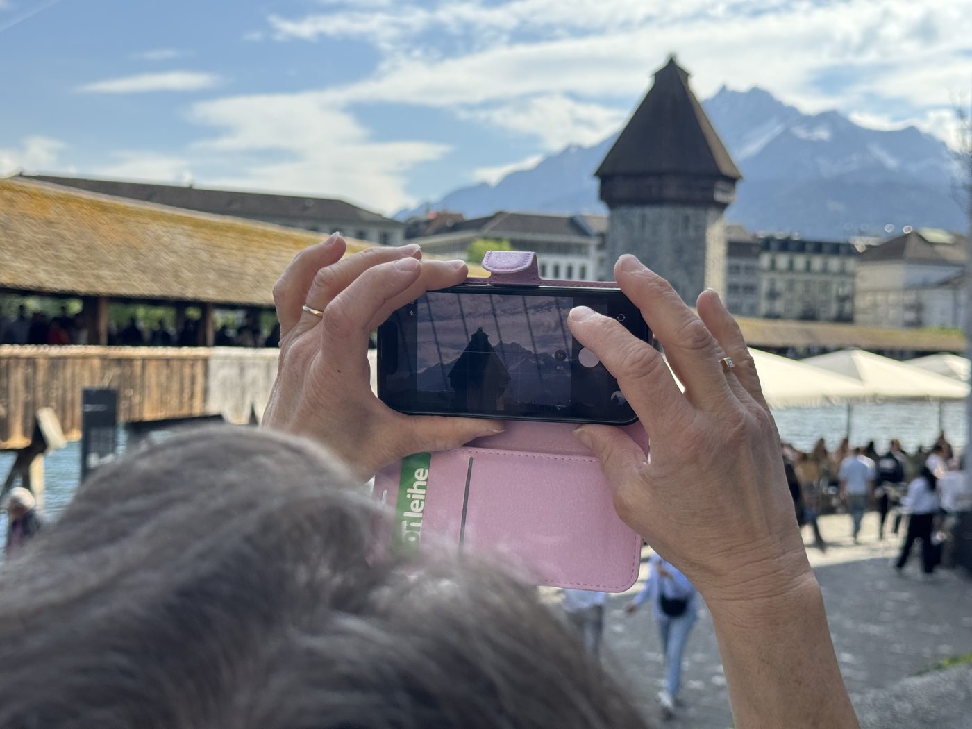 Zwei Hände halten ein iPhone quer und fotografieren den Wasserturm in Luzern